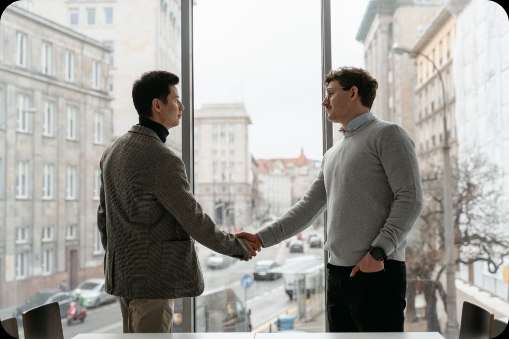 Business partners shaking hands in office window